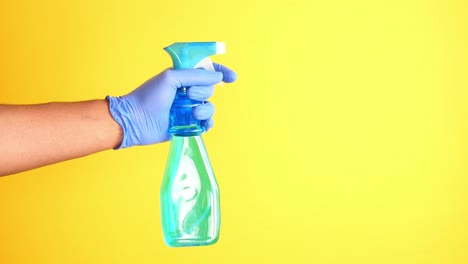 person in blue gloves holding a spray bottle