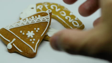Hand-takeout-pastry-gingerbread-with-white-decoration-on-top-in-various-shapes-lying-on-top-of-each-other-on-a-white-background