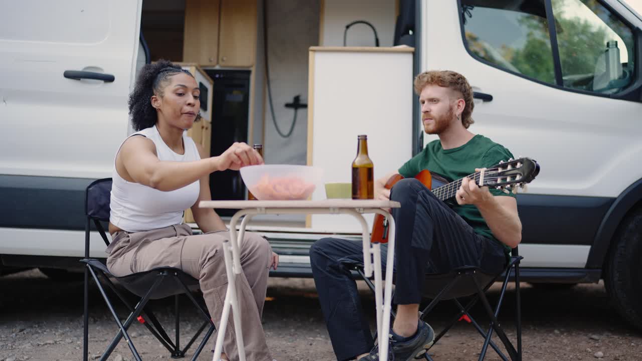 Couple enjoying music and snacks during a van life adventure