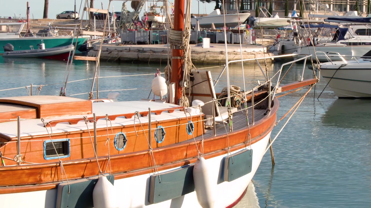 Inquadratura media statica di uno yacht in legno d'epoca attraccato in un luminoso porto francese.