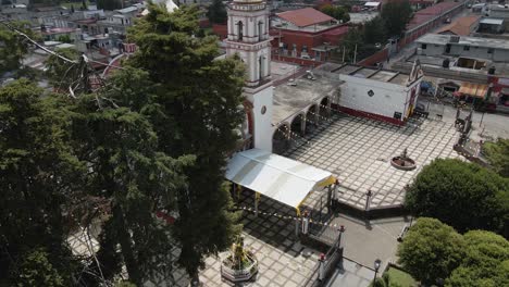 Aerial-view-of-the-church-peeking-out-from-behind-the-beautiful-trees-in-Mexico