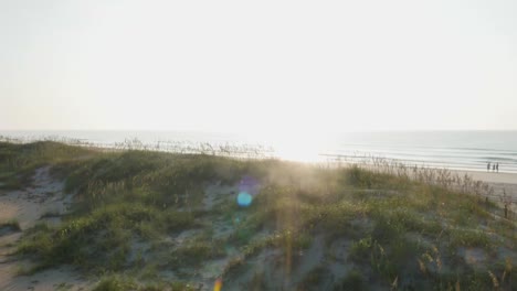 4k view of beach access rising over the dunes to reveal the ocean at sunrise with lens flare