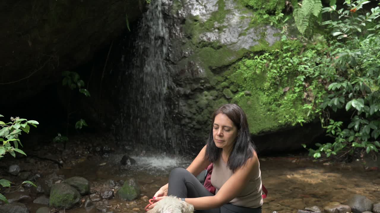 mujer joven y su perro en una cascada en el bosque tropical. cascada en un bosque verde. concepto de turismo sostenible. caminata en el bosque green. concepto de trekking. amatlan, méxico