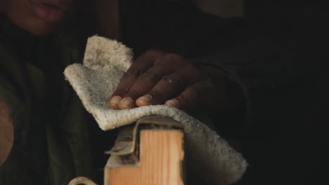 shepherd's hand wiping dirt on stable door of a barn with a rag - close up