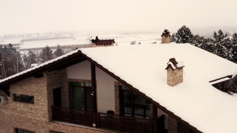 Aerial-Drone-Flying-Over-Home-Covered-in-Snow-Revealing-a-Beautiful-Snow-Covered-Forest