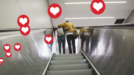 Animation-of-heart-icons-floating-over-couple-embracing-on-moving-stairs