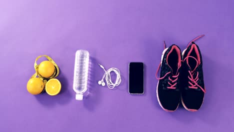 Mobile-phone-with-headphones,-shoes,-water-bottle,-lemon-and-measuring-tape