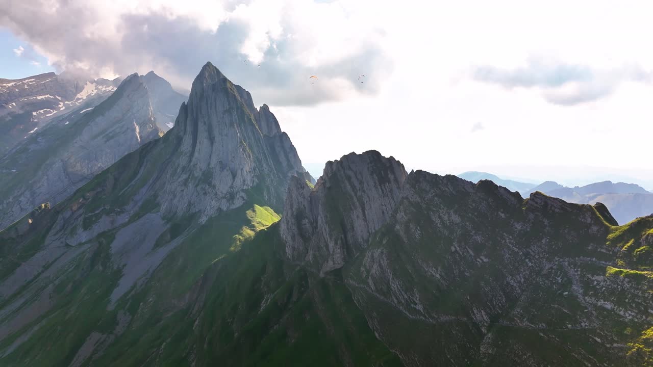 Drone footage showcases the iconic Schäfler mountain in Switzerland, with its razor-sharp ridgeline and steep cliffs bathed in golden light, drone pulling away