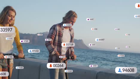 Múltiples-íconos-Digitales-Con-Números-Cada-Vez-Mayores-Sobre-Una-Pareja-Caucásica-Montando-Scooters-Eléctricos