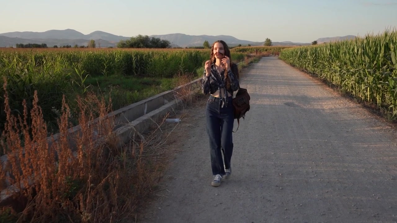 Una giovane donna si gode una passeggiata tranquilla attraverso campi di mais rigogliosi all'ora del tramonto.