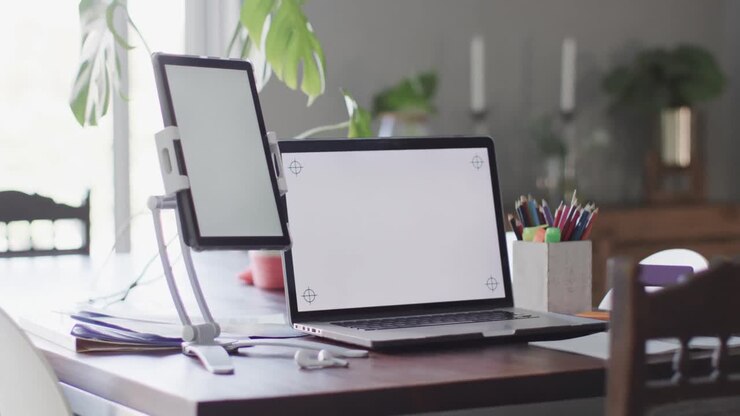 Tomt værelse med bærbar computer og tablet med plads til indhold på skærmene på et bord i slowmotion.