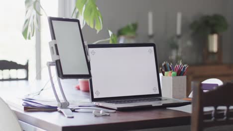 habitación de la casa vacía con portátil y tableta con espacio de copia en las pantallas en la mesa en cámara lenta.