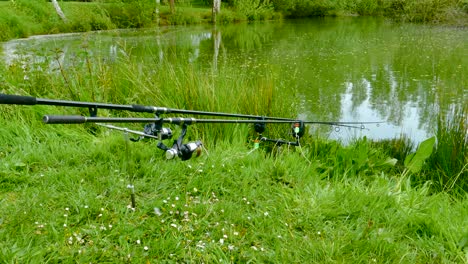 two fishing rods resting on the riverbank at fishery woodlands pond in norwich