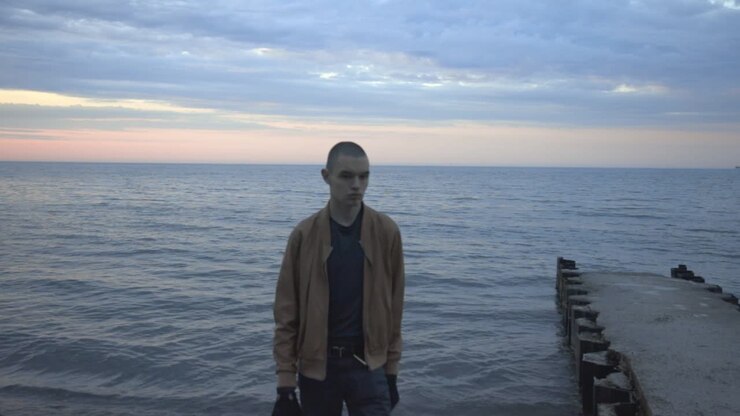 Giovane con una macchina fotografica che lascia la riva all'alba - Campo medio (Slow Motion)