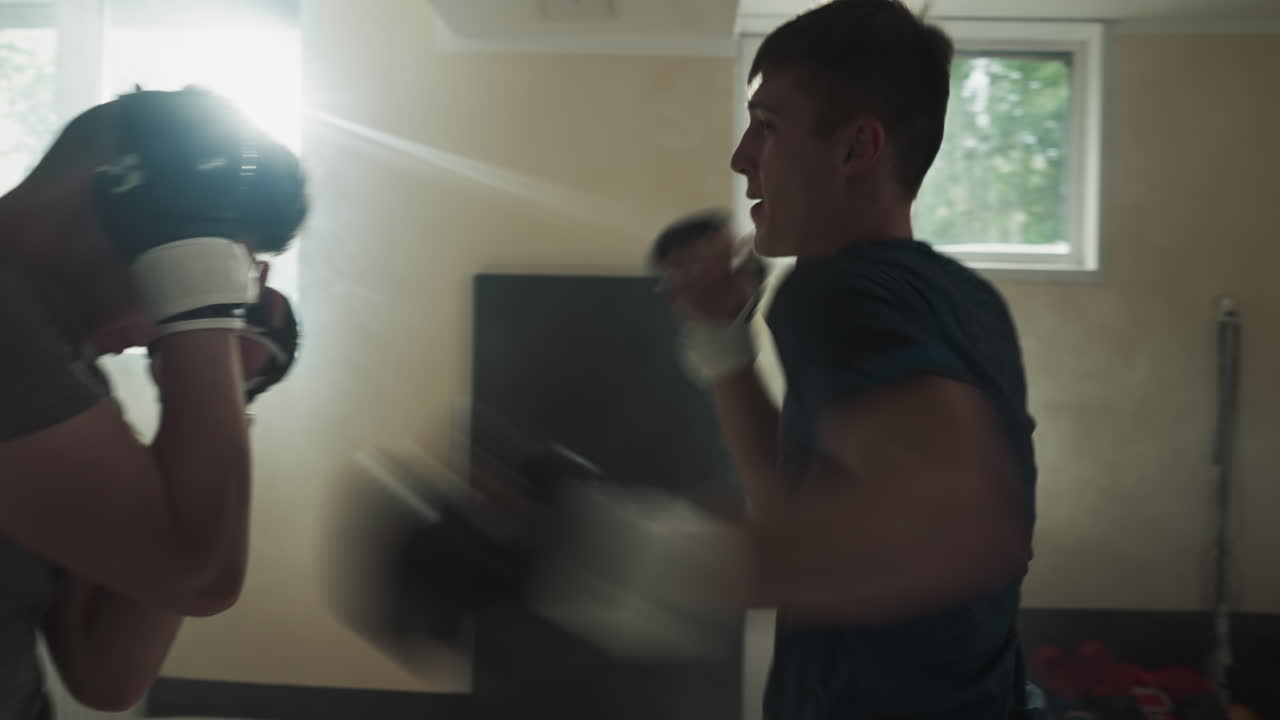 스포츠 클럽에서 친절한 스파링을 수행하는 싸움: 남자 블록 타격과 타격은 체육관에서 느린 동작에서 파트너와 싸운다. 혼합 무술 선수