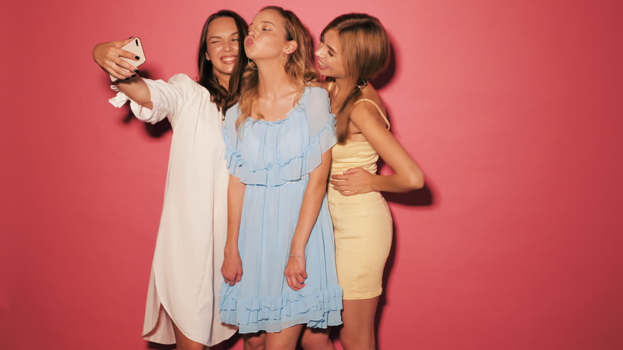 tres mujeres jóvenes tomando una selfie en vestidos