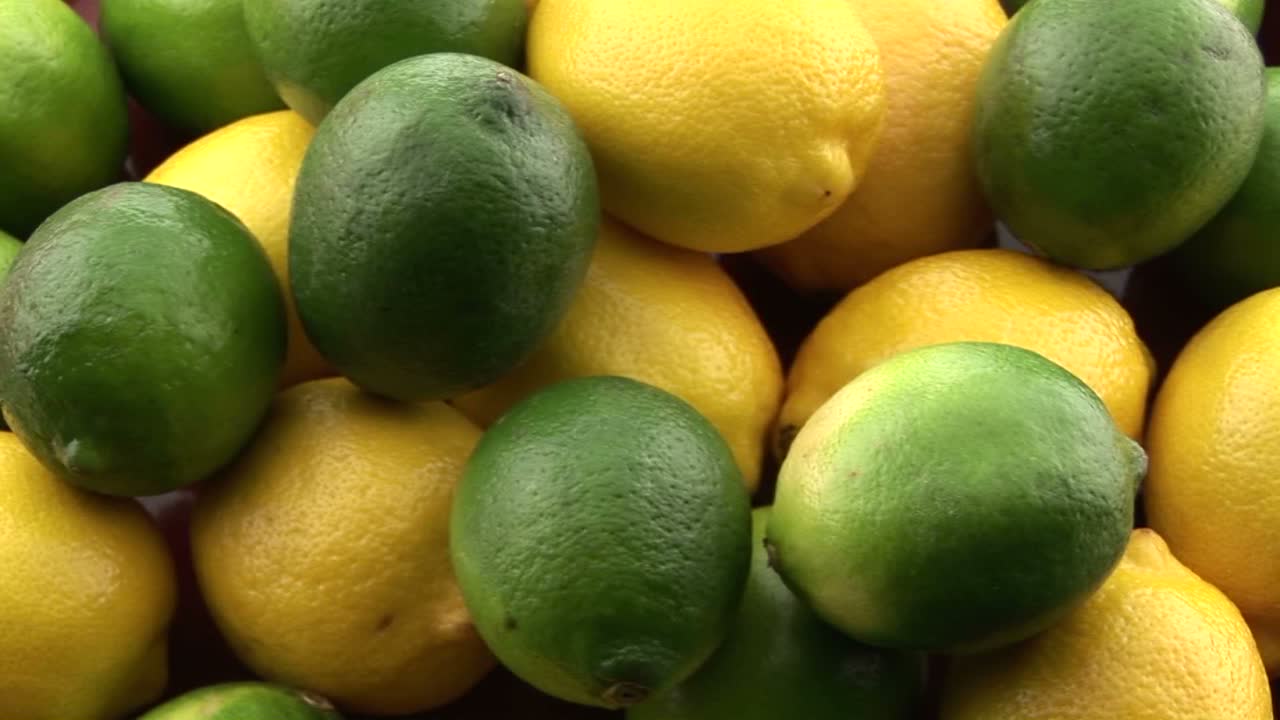 zoom lento en limones amarillos sentados en una pila con limas verdes