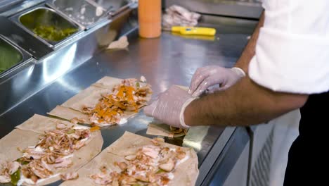 chef rodando sándwich de shawarma de pollo sirio y poniendo aceite en él