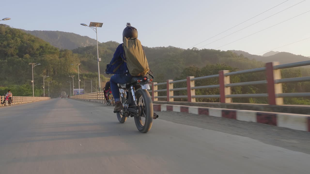 Motociclista su un ponte all'alba
