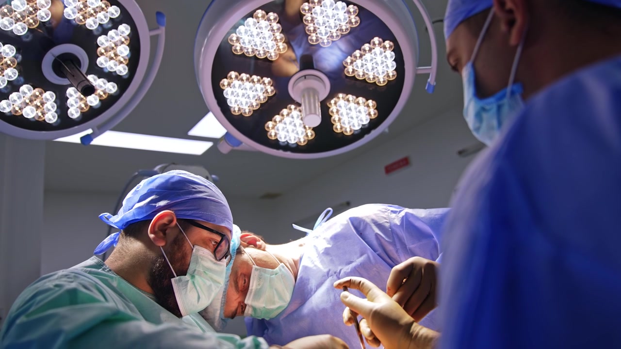 Due chirurghi lavorano sotto la moderna attrezzatura di illuminazione nella sala operatoria. Operazione traumatologica sotto luminose lampade rotonde. Vista dal basso.