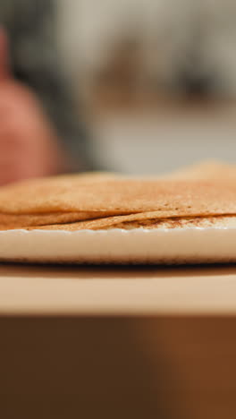 manos femeninas con pañuelo blanco poner panqueques dulces en la mesa. cena y conversación agradable en la familia amorosa. descanso de la noche en casa en el fondo borroso primer plano