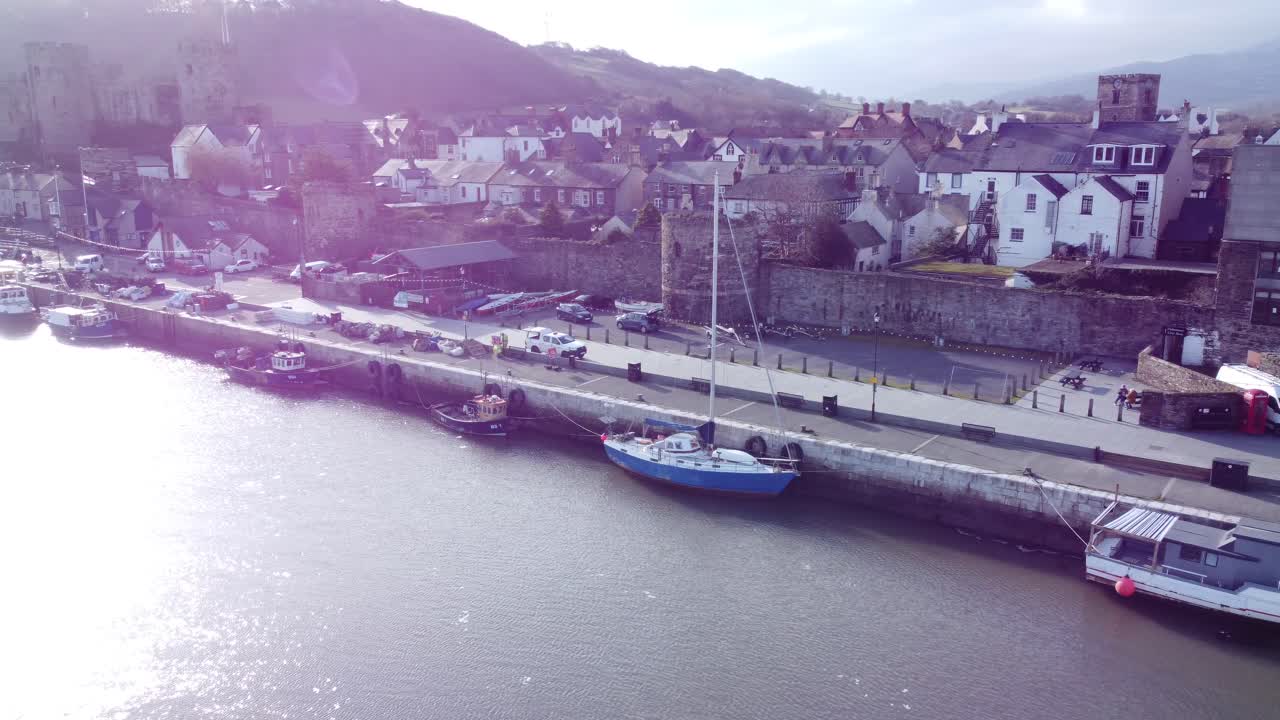 목가적인 콘위 성(conwy castle)과 항구 어촌 마을 보트는 반짝이는 물을 가로질러 남겨진 해안가 공중 돌리에 있습니다.