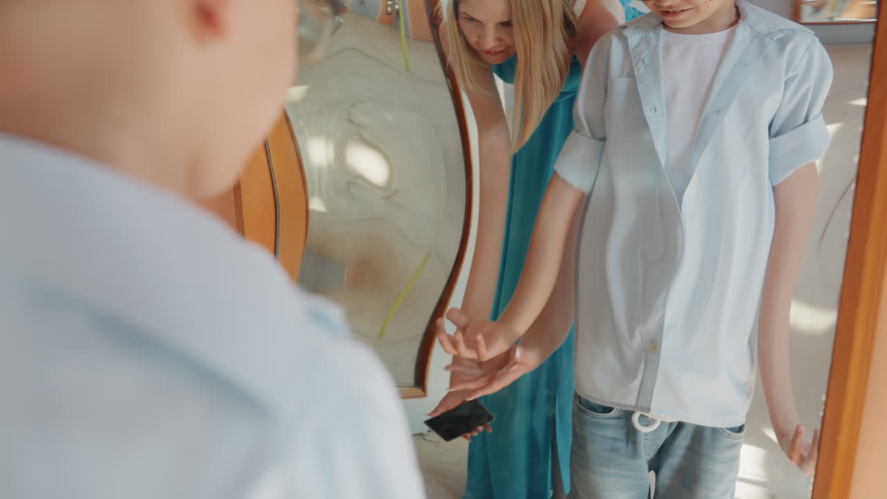 Familieudflugt med smilende børn. Reflekterede børn holder i hånd i fredelig familiepark. Kaukasiske børn deler et ømt øjeblik under solrig weekend udendørs familieaktivitet.