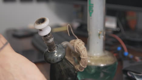 flames and embers shoot through the stem of a bong as a bowl of marijuana is smoked