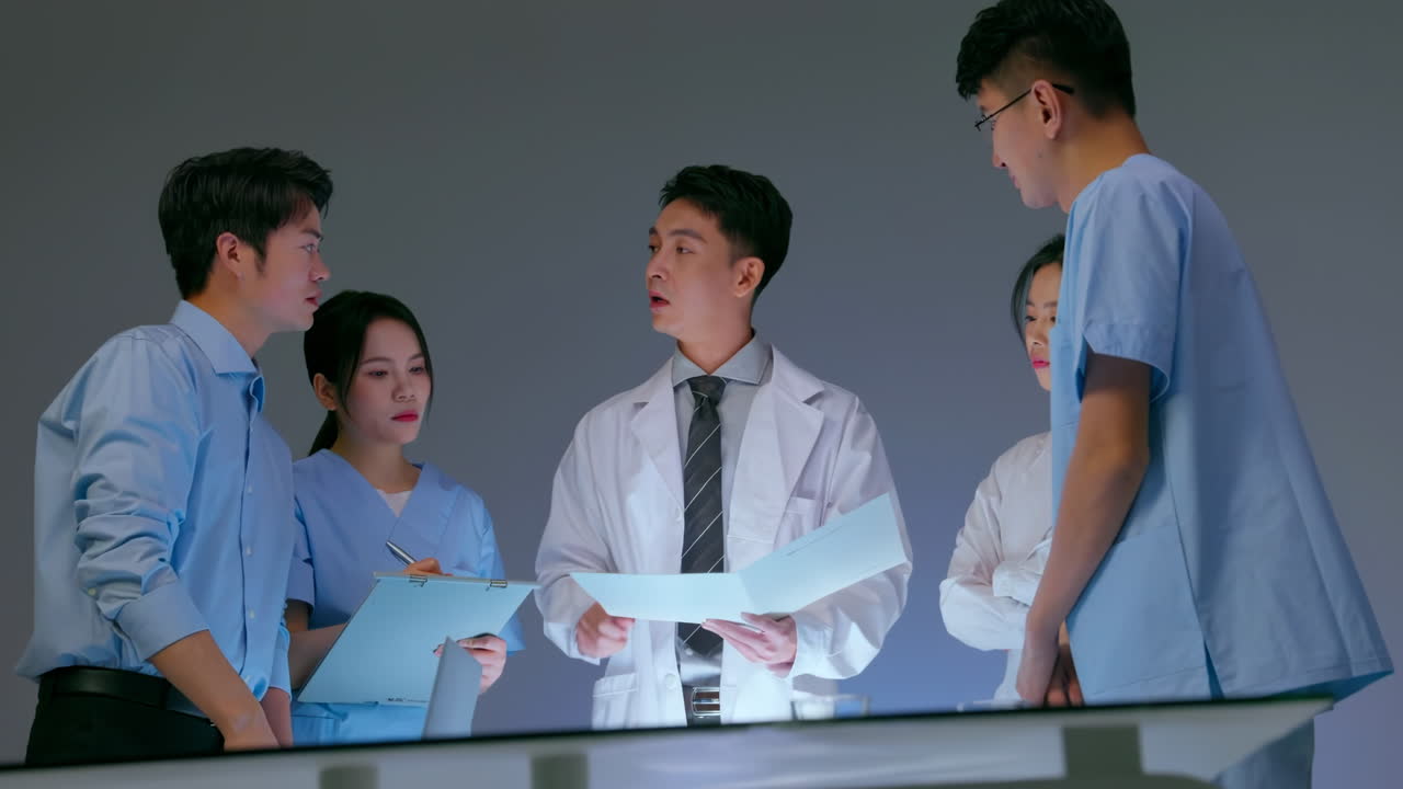 Professional Clinic therapist talking with colleagues about disease. Team experts medical having meeting, using laptop and paper documents examining medical reports during work day in the hospital