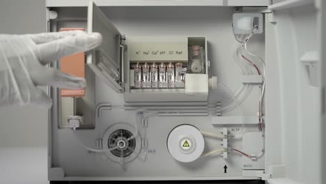 static shot of gloved hand operating blood cbc machine