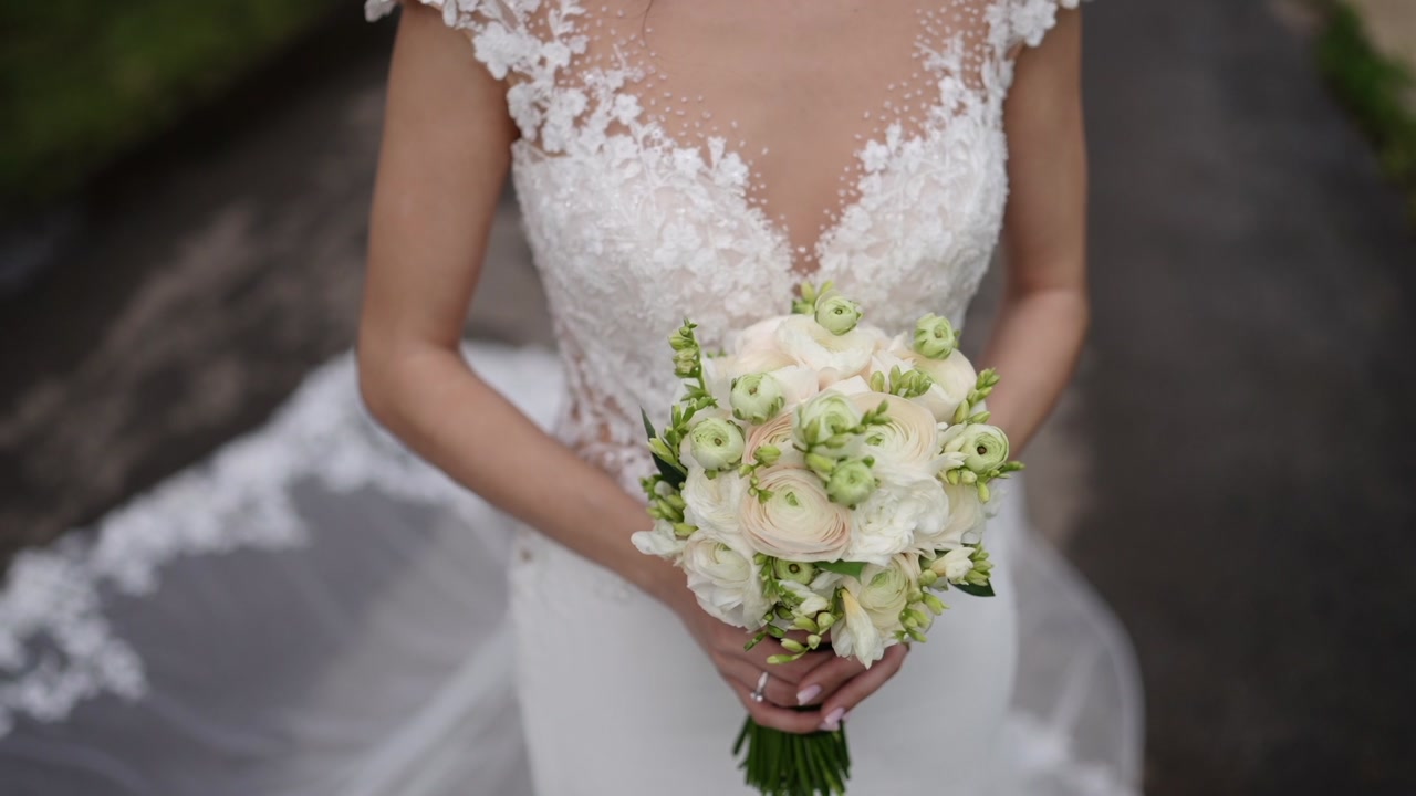Bride holding flower bouquet in lace wedding dress close up