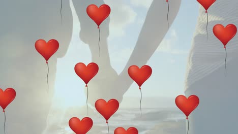 Multiple-heart-shaped-balloons-floating-against-mid-section-of-couple-holding-hands