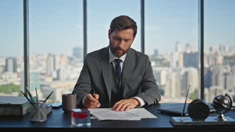 hombre de negocios firmando papeles corporativos en la oficina. exitoso gerente barbudo leer