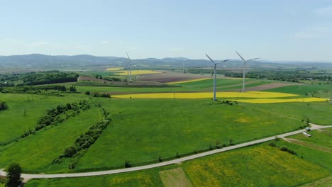 Wind-turbines-in-farm-stand-above-yellow-and-green-rapeseed-fields-in-poland