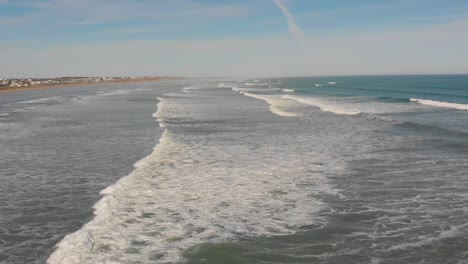 Aerial-view-stationary-of-waves-rolling-onto-a-beach-in-Middleton,-South-Australia