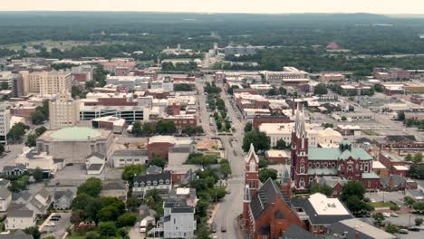 an aerial shot of downtown macon, ga, with views of the st. joseph church, poplar street, and the forests in the distance