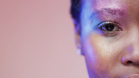 Eye-of-african-american-woman-with-short-dark-hair-in-blue-light-with-copy-space,-slow-motion