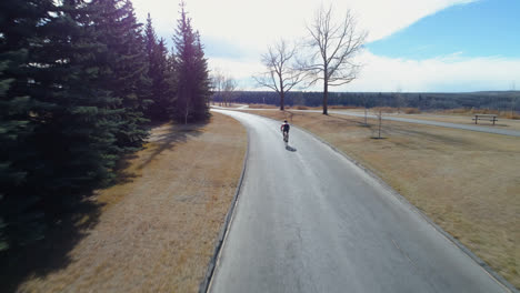 cyclist cycling through a country road in forest 4k