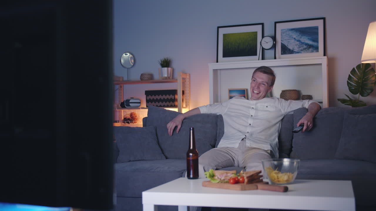 Mand slapper af på sofaen og ser tv om aftenen