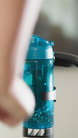 mujer vuelve a poner una botella de agua en el soporte de la cinta de correr. deportista sigue corriendo después de tomar sorbos de agua en un club de fitness. mantenimiento de los niveles de hidratación durante el entrenamiento