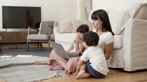 mom showing content on laptop to two kids