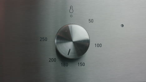 mano masculina girando la temperatura del horno a 180 grados