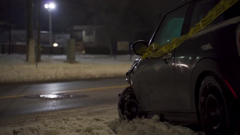 secuelas de un accidente automovilístico en una noche de invierno en la nieve con un vehículo pequeño envuelto en cinta de precaución