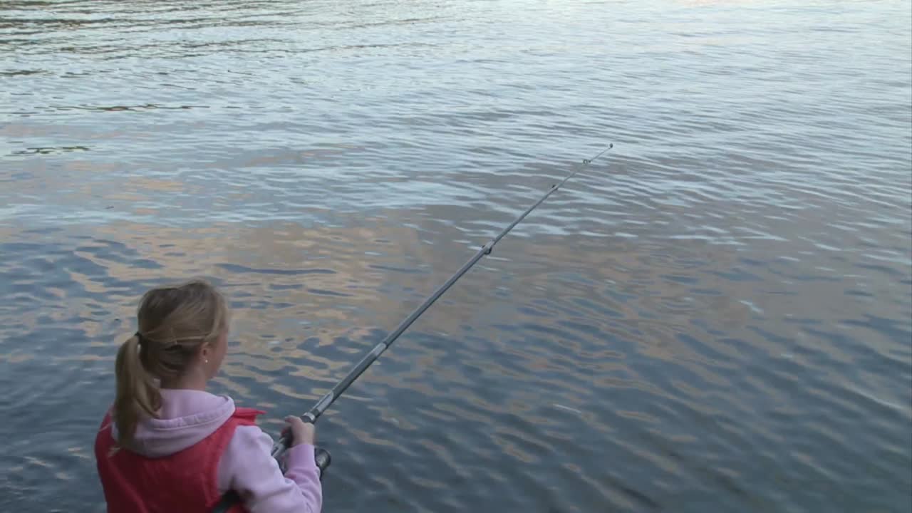Seorang wanita memancing di bebatuan