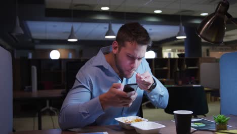 businessman working and eating in a modern office by night