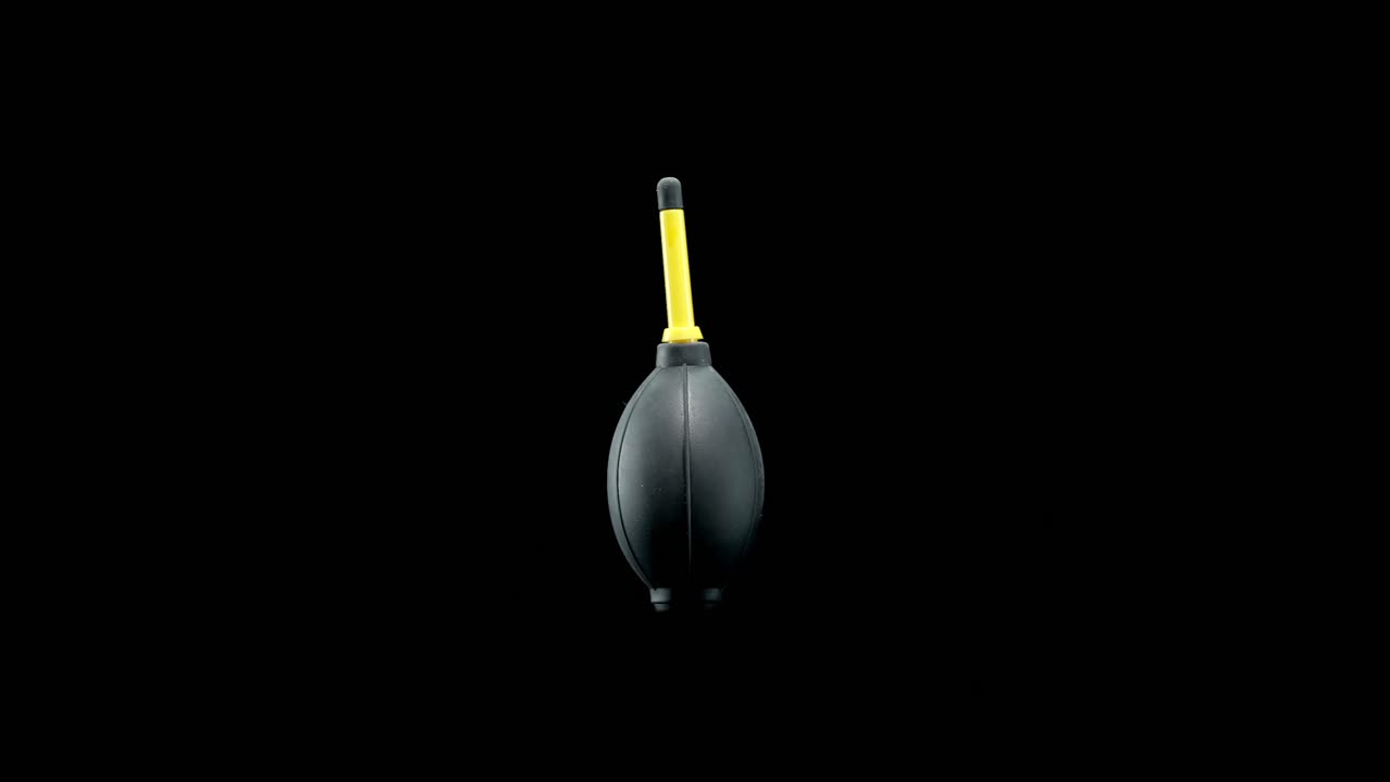 Hand squeeze air blower bulb rotating on black background for cleaning dust