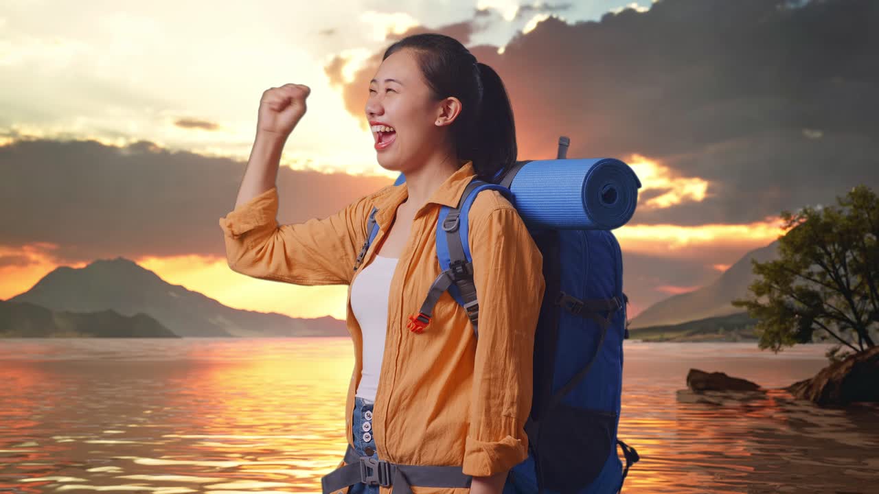 Side View Of Asian Female Hiker With Mountaineering Backpack Screaming Goal Celebrating The Success While Standing At A Lake During Sunset Time