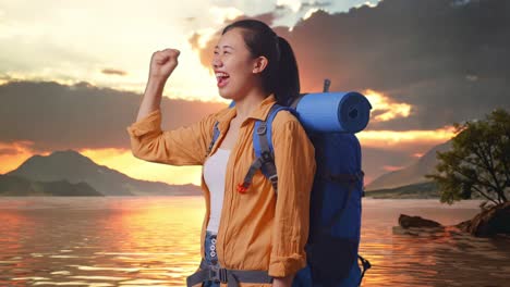 side view of asian female hiker with mountaineering backpack screaming goal celebrating the success while standing at a lake during sunset time