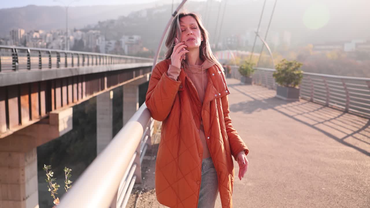 Una donna fa una telefonata urgente su un ponte durante il tragitto giornaliero in città.