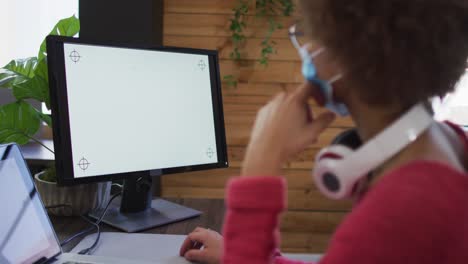 Mid-section-of-african-american-woman-having-a-video-chat-on-her-computer-at-modern-office